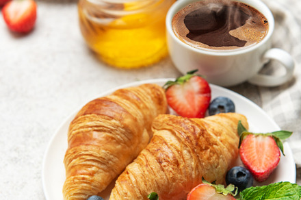 Delicious breakfast with croissants, coffee, berries and honey e