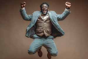 Joyful guy jumping in celebration in formal outfit on beige background, a Person Photo by AS photostudio