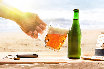 Hand with beer mug celebrating holidays with beach background., a Food & Drink Photo by Davizro's Market