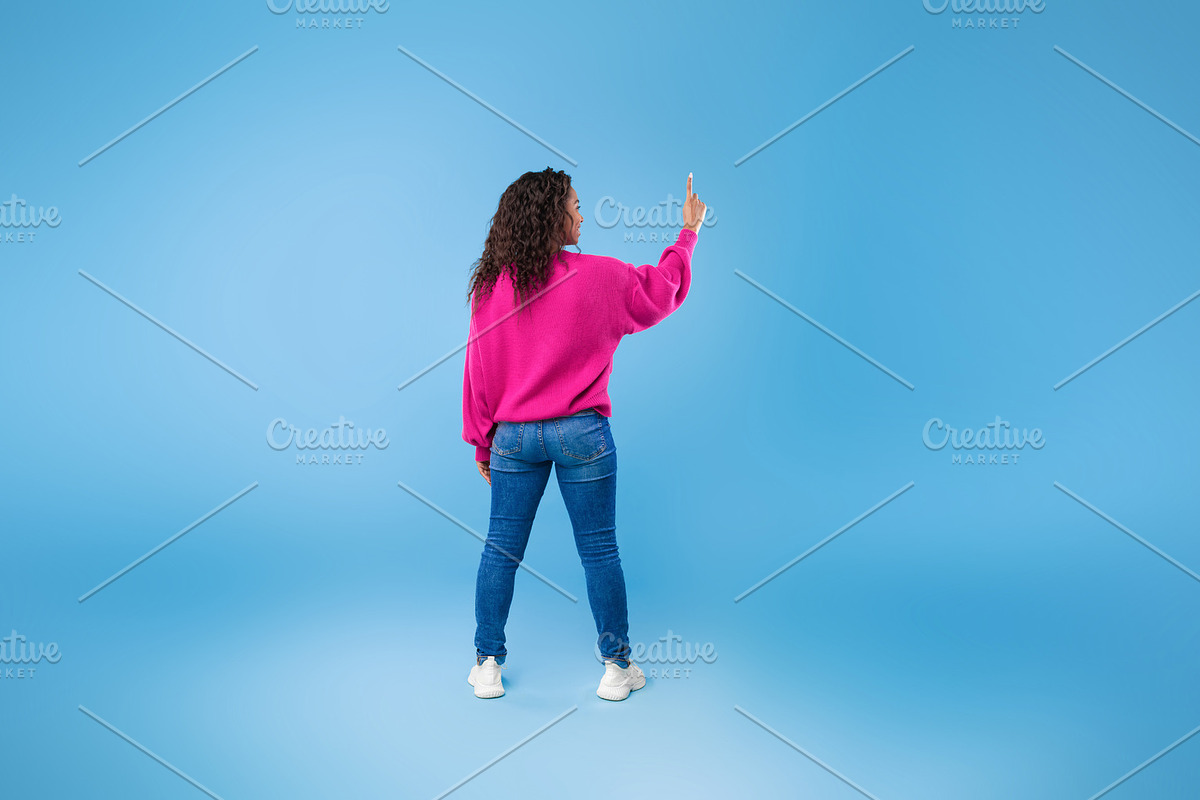 Back view of millennial African American lady touching imaginary screen, pressi, a Photo by Prostock-Studio (Photo 1 of 2)