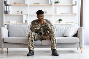 Pensive african american soldier in military uniform sitting on couch, a Photo by Prostock-Studio