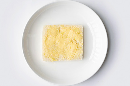 Butter on a slice of bread isolated on white background on a pla, a Food & Drink Photo by Tampatra