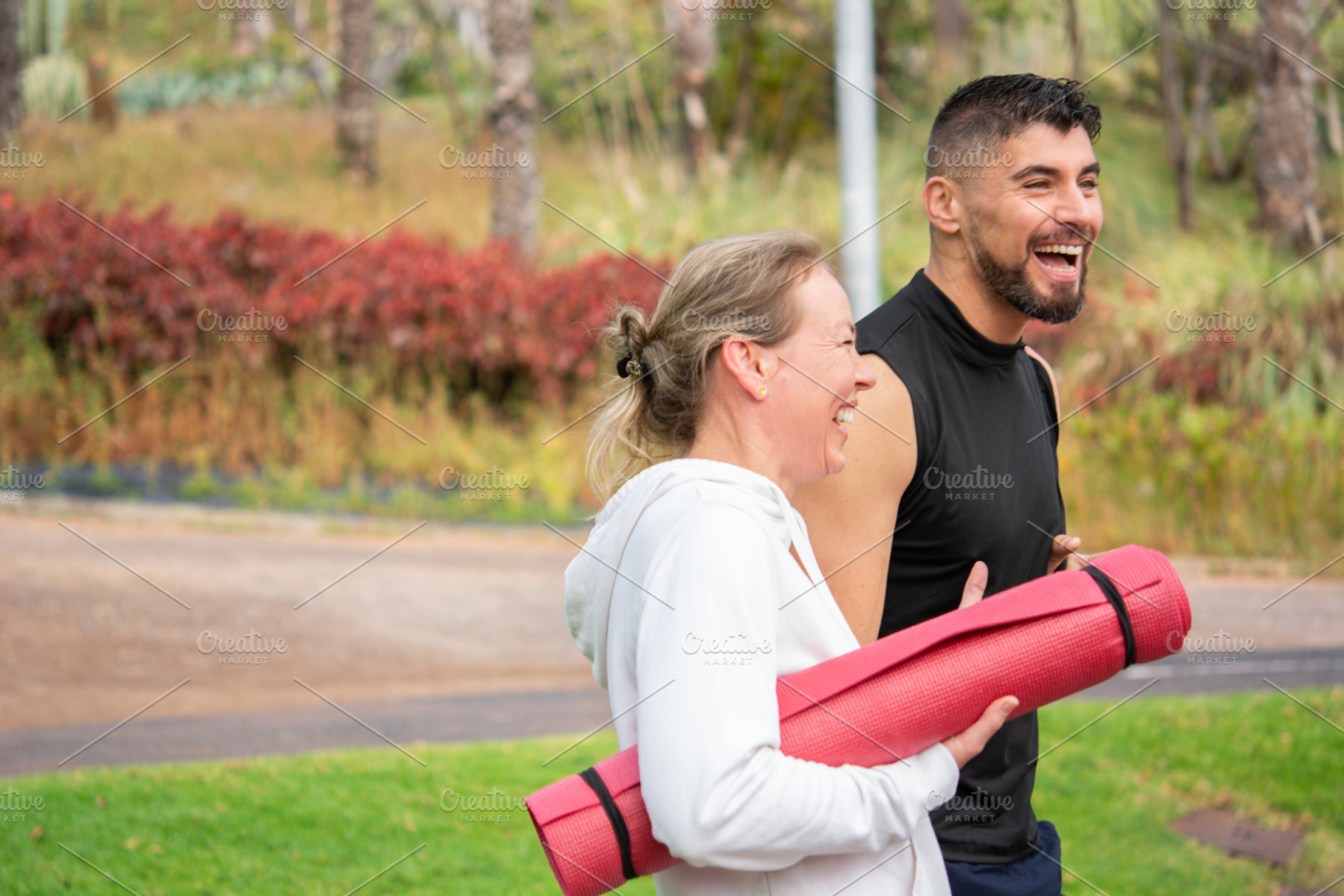 Active couple walking in park after workout carrying yoga mats, a Sports & Recreation Photo by etorres69