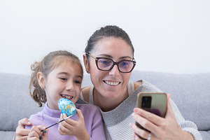 Mother and daughter taking a selfie while decorating Easter eggs at home, a Food & Drink Photo by etorres69