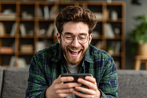 Happy man using smartphone laughing, a Photo by Pixeness Studio