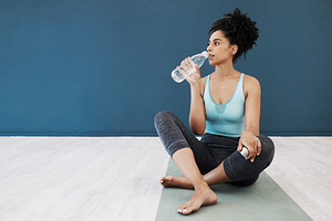 Tired, fitness or woman drinking water in gym for fitness training, workout exercise or health. Athlete, wellness or relax girl with water bottle for sport hydration, mockup or rest energy in studio, a Photo by Peopleimages.com