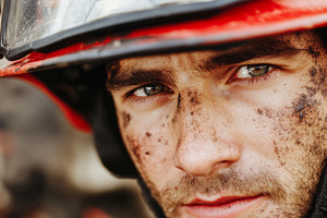 Firefighter in yellow helmet with soot-covered face and uniform,, a Photo by Dvoevnore photos