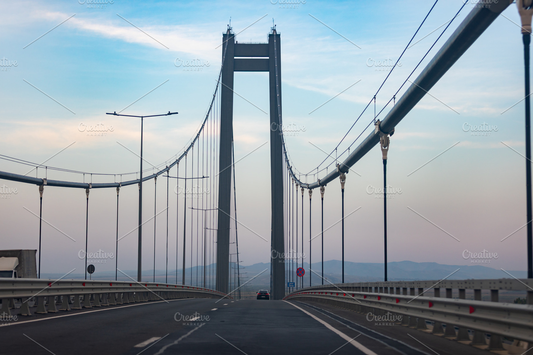 Wide angle view of an empty suspension bridge at dawn, featuring clear blue sky, an Architecture Photo by Ales Munt
