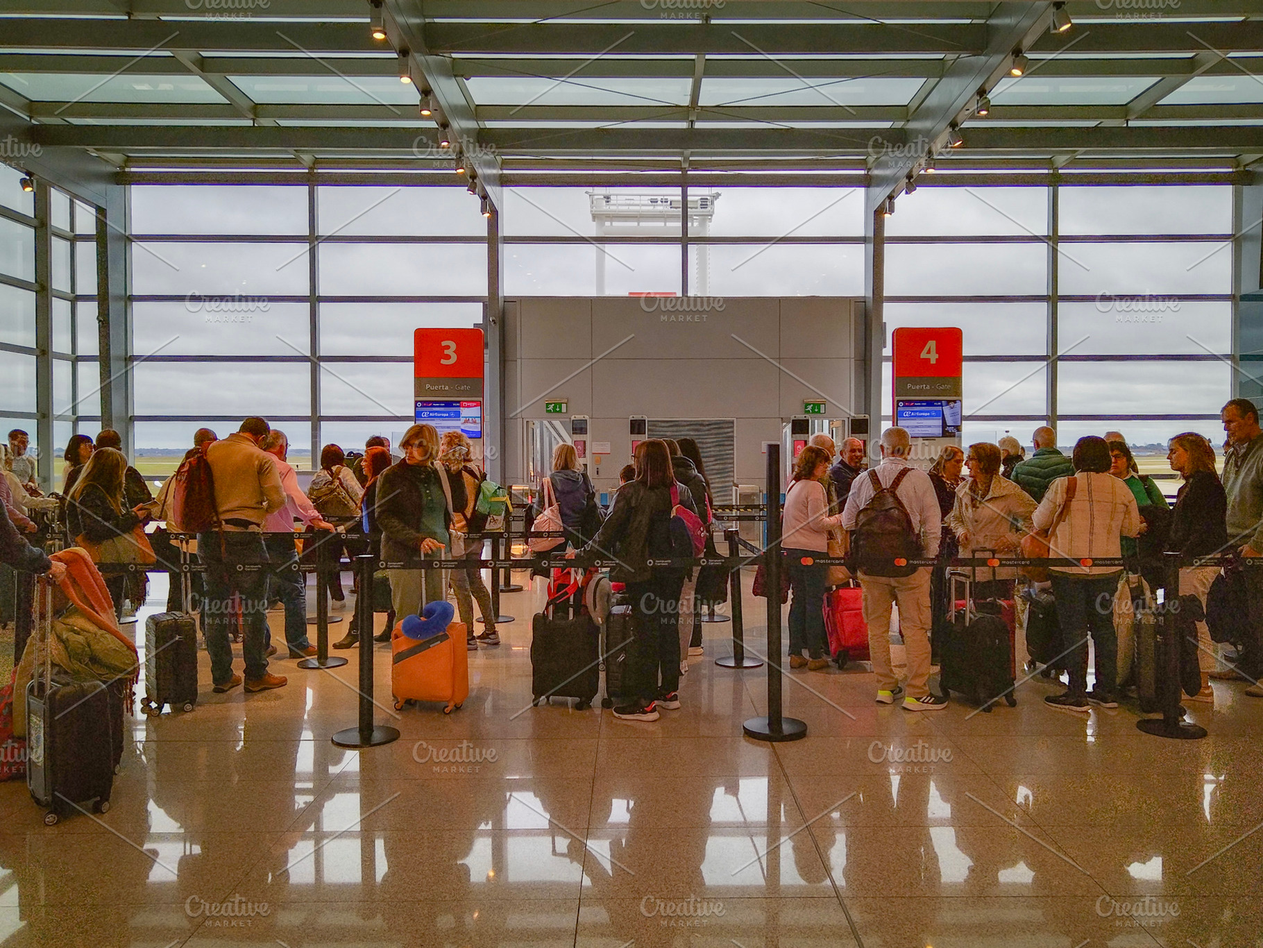 Crowded airport boarding area with travelers and luggage, a Transportation Photo by DanFLCreativo