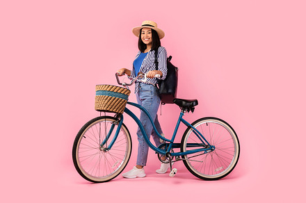 Asian woman standing with retro bicycle with wicker basket, a Background Photo by Prostock-Studio