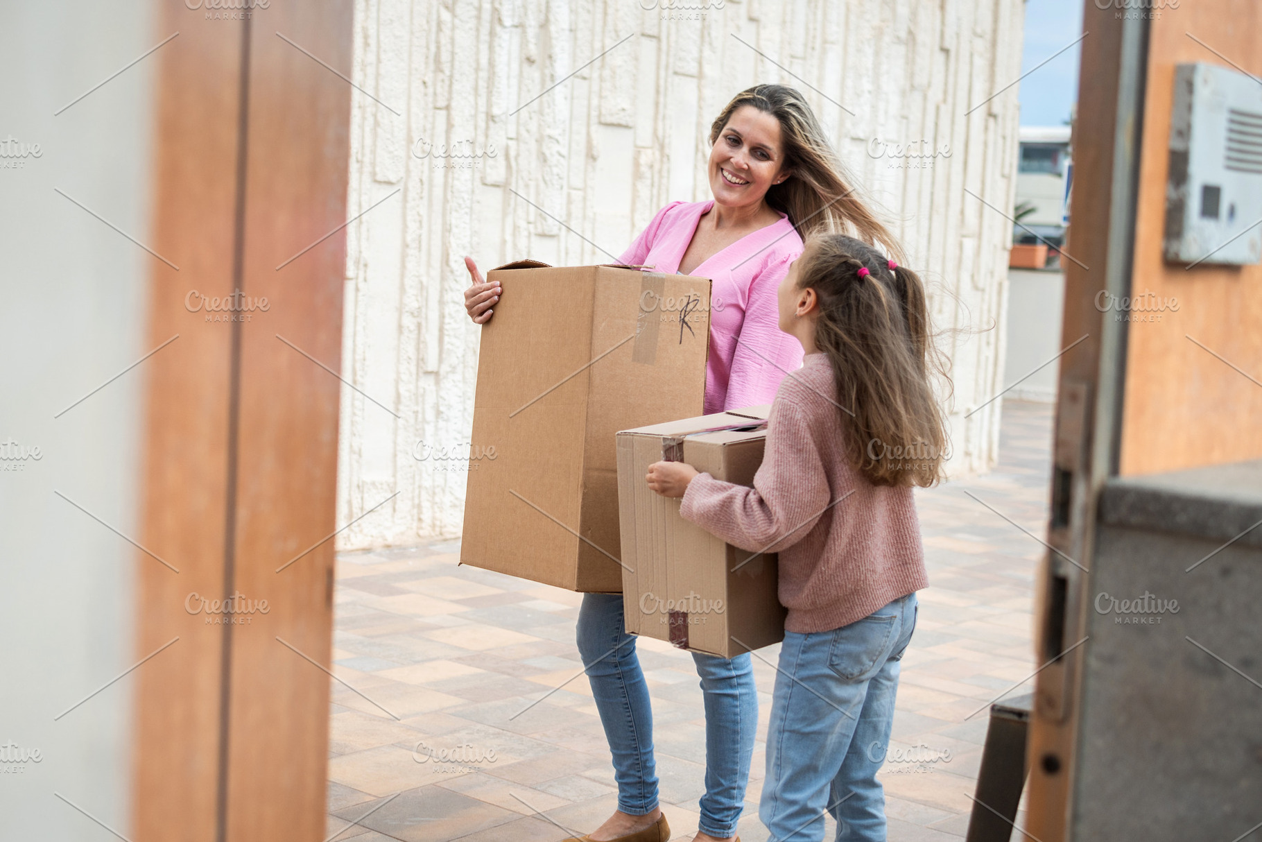 Mother and Daughter Carrying Moving Boxes Into New Home on Moving Day, a Person Photo by etorres69
