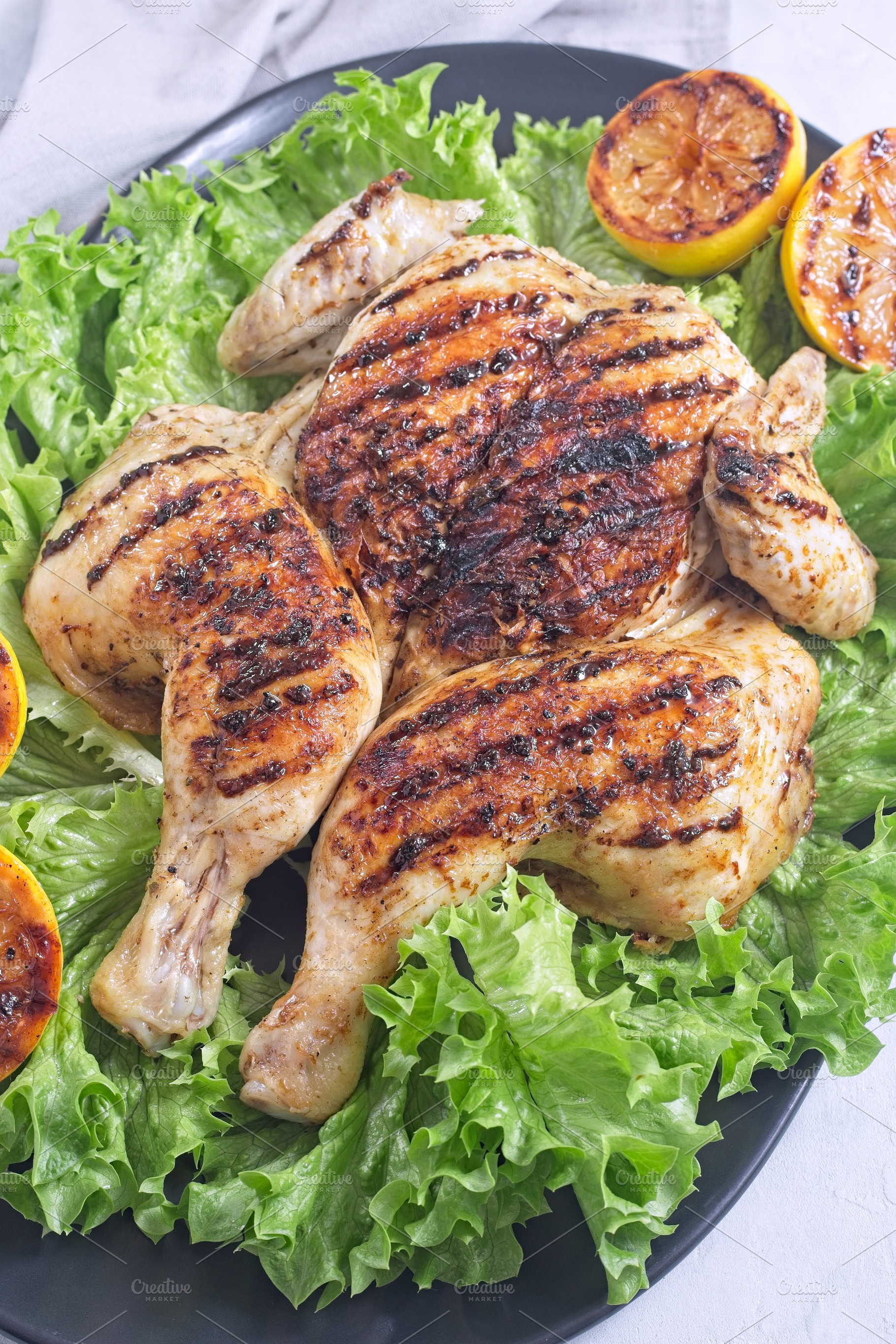 Grilled spatchcocked chicken with lemon garlic marinade on lettuce with lemon h, a Food & Drink Photo by iuliia_n