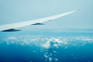 Airplane wing flying above the clouds during daylight flight, a Transportation Photo by GoodGoods