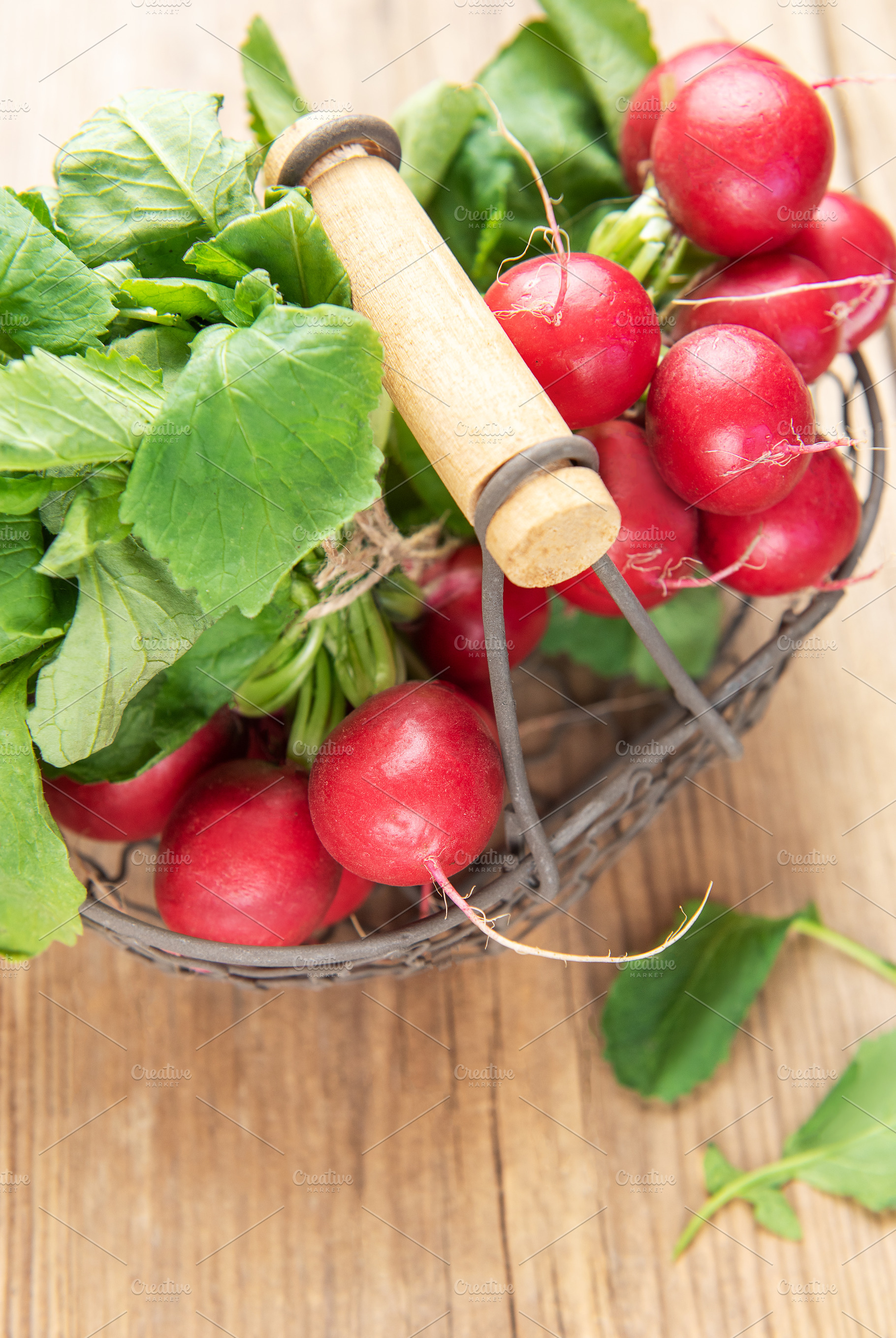 Fresh red radishes with green leaves in basket on wood, a Food & Drink Photo by Olena Rudo