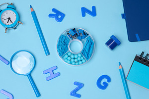 Flat lay of blue stationery, learning items letters, magnifying, a School & Education Photo by ndanko