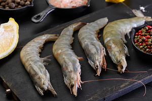 Raw shrimp with spices on a wooden board, a Food & Drink Photo by ndanko