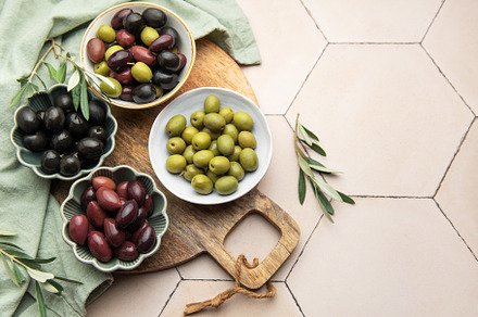 Green, black and kalamata olives in bowls on wooden board, a Food & Drink Photo by Olena Rudo