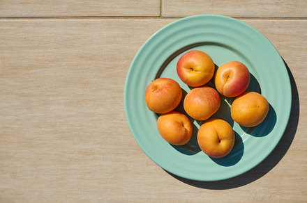 Fresh apricots on turquoise plate with beige background