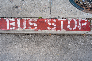 Worn-out bus stop sign painted on a red curb in San Francisco, an Architecture Photo by GoodGoods