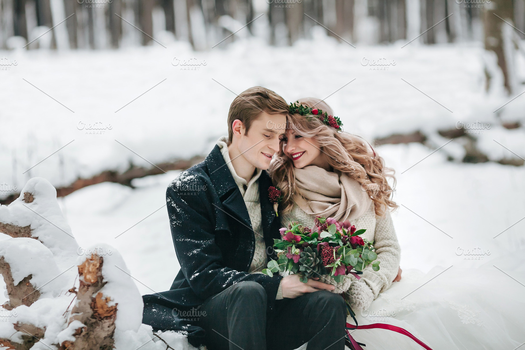 Cute couple in love with a bouquet are sitting on the log on background of the winter forest. Artwork, a Food & Drink Photo by Stahov