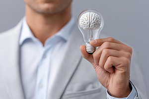 A person holds a unique light bulb that contains a brain design, symbolizing in, a Technology Photo by AlyaAnd