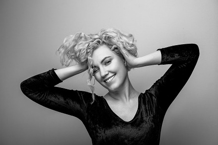 Headshot of gorgeous attractive young lady with curly hair smiling. Black and w