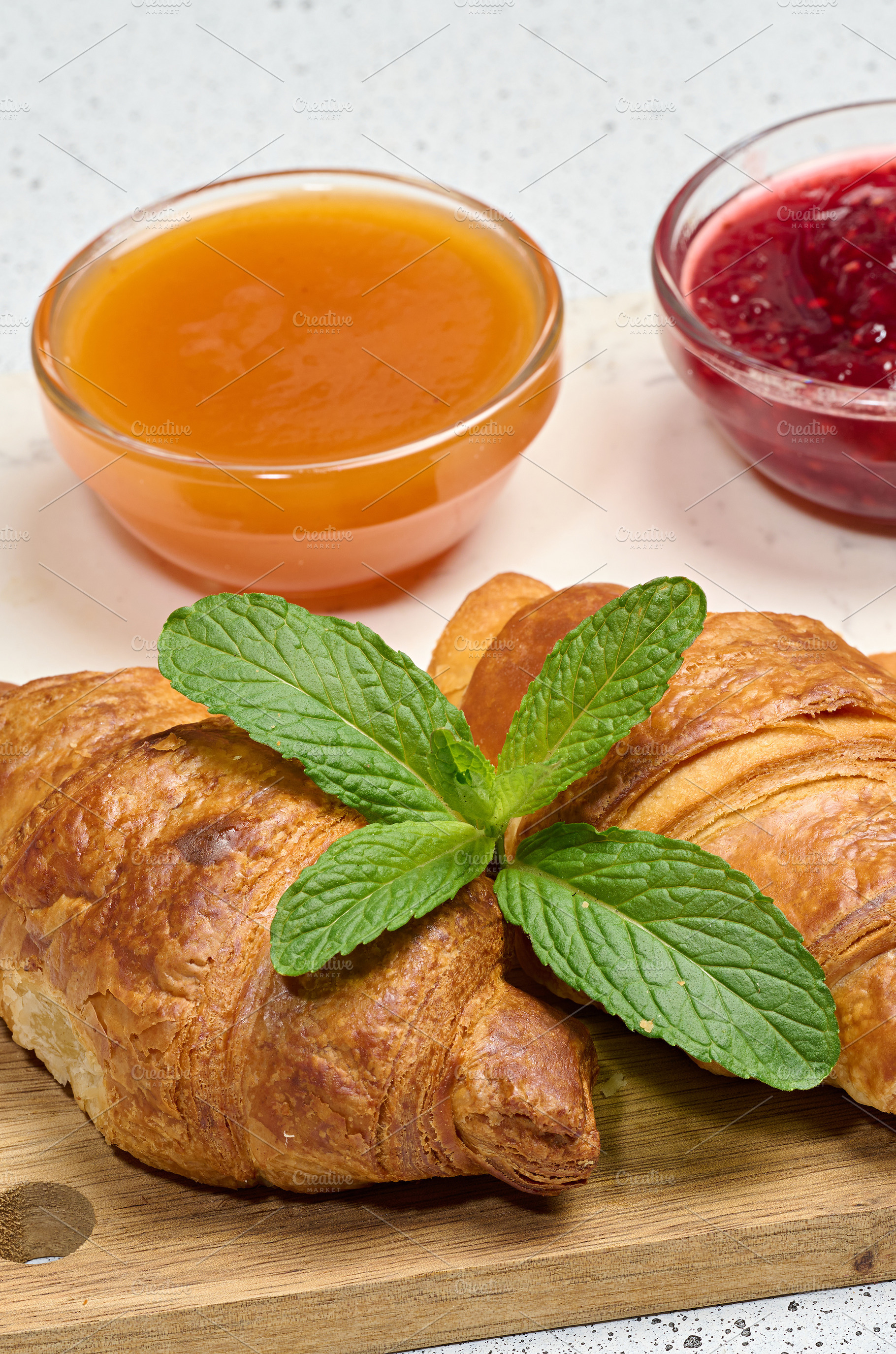 Fresh golden croissants on a wooden board with fruit jam and min, a Food & Drink Photo by ndanko