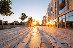 Long shadows cast by a vibrant sunset along the urban street with reflective bu, a Photo by AlyaAnd