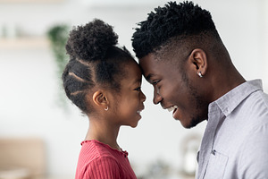 Side view of cute black father and daughter touching foreheads, a Photo by Prostock-Studio