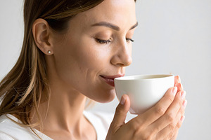 Woman enjoying morning tea with gentle satisfied expression, a Person Photo by GoodGoods