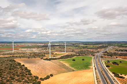 Wind turbines spread across farmland with intersecting highways