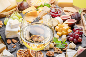 Glass of white wine with variety of sliced cheeses., a Food & Drink Photo by Volff