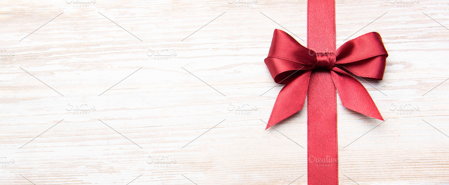 Red festive bow and ribbon on wooden background, a Holiday Photo by Olena Rudo