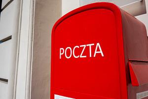 Red mailbox with 'Poczta' text against a wall in Warsaw, Poland, a Photo by AS photostudio
