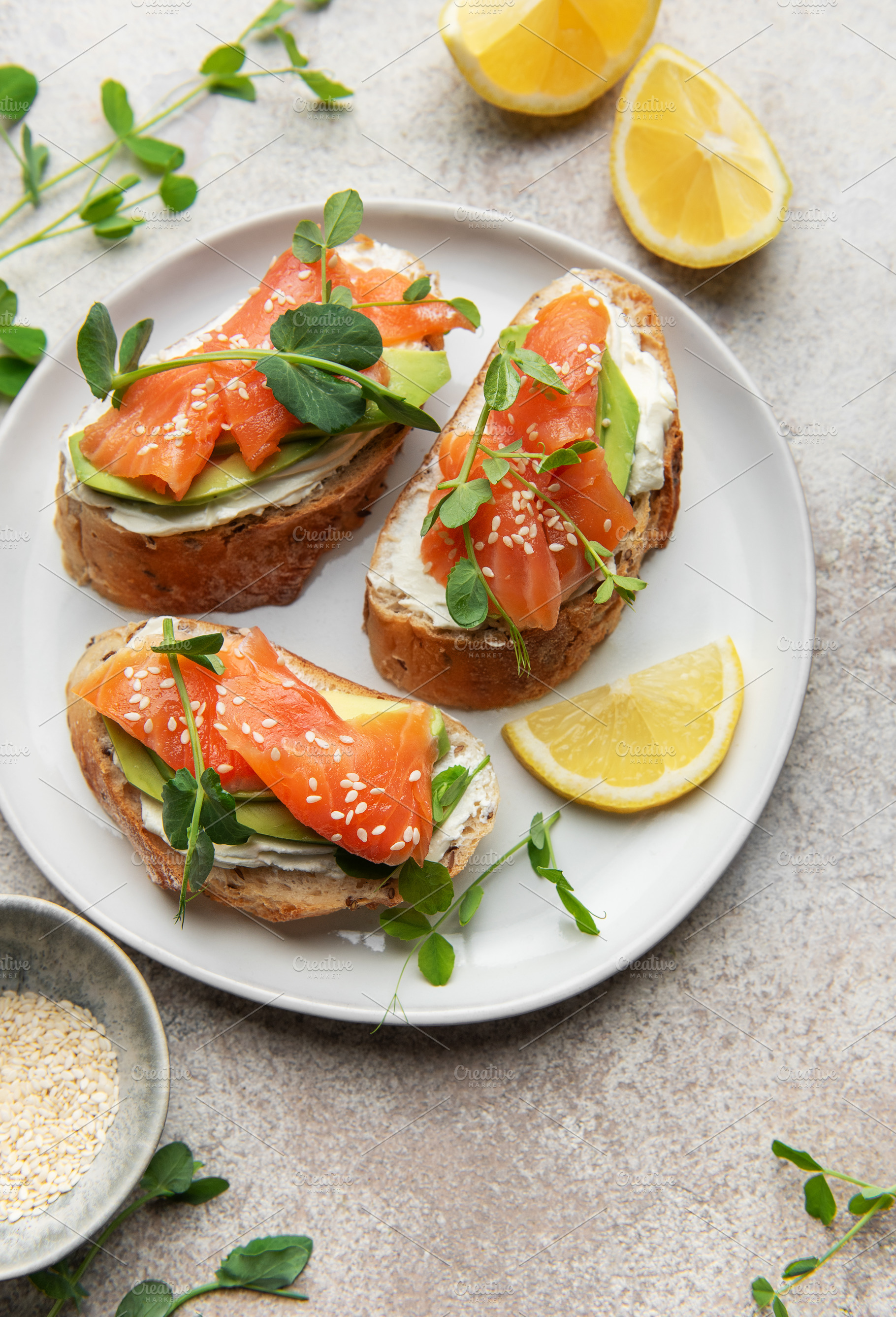 Salmon avocado toasts with cream cheese and lemon on plate, a Food & Drink Photo by Olena Rudo