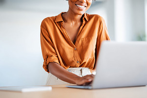 Smiling woman working on laptop in modern office, a Business Photo by AlyaAnd