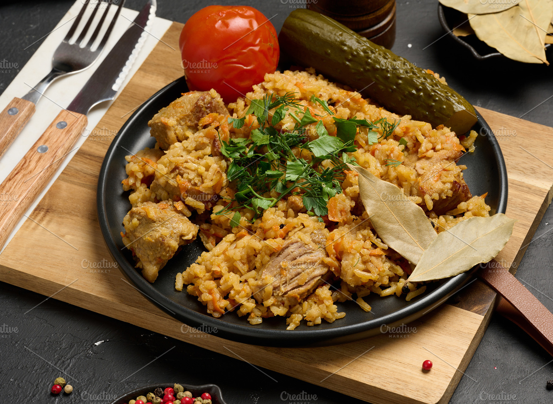 Pilaf with pieces of meat and herbs served on a black plate with, a Food & Drink Photo by ndanko