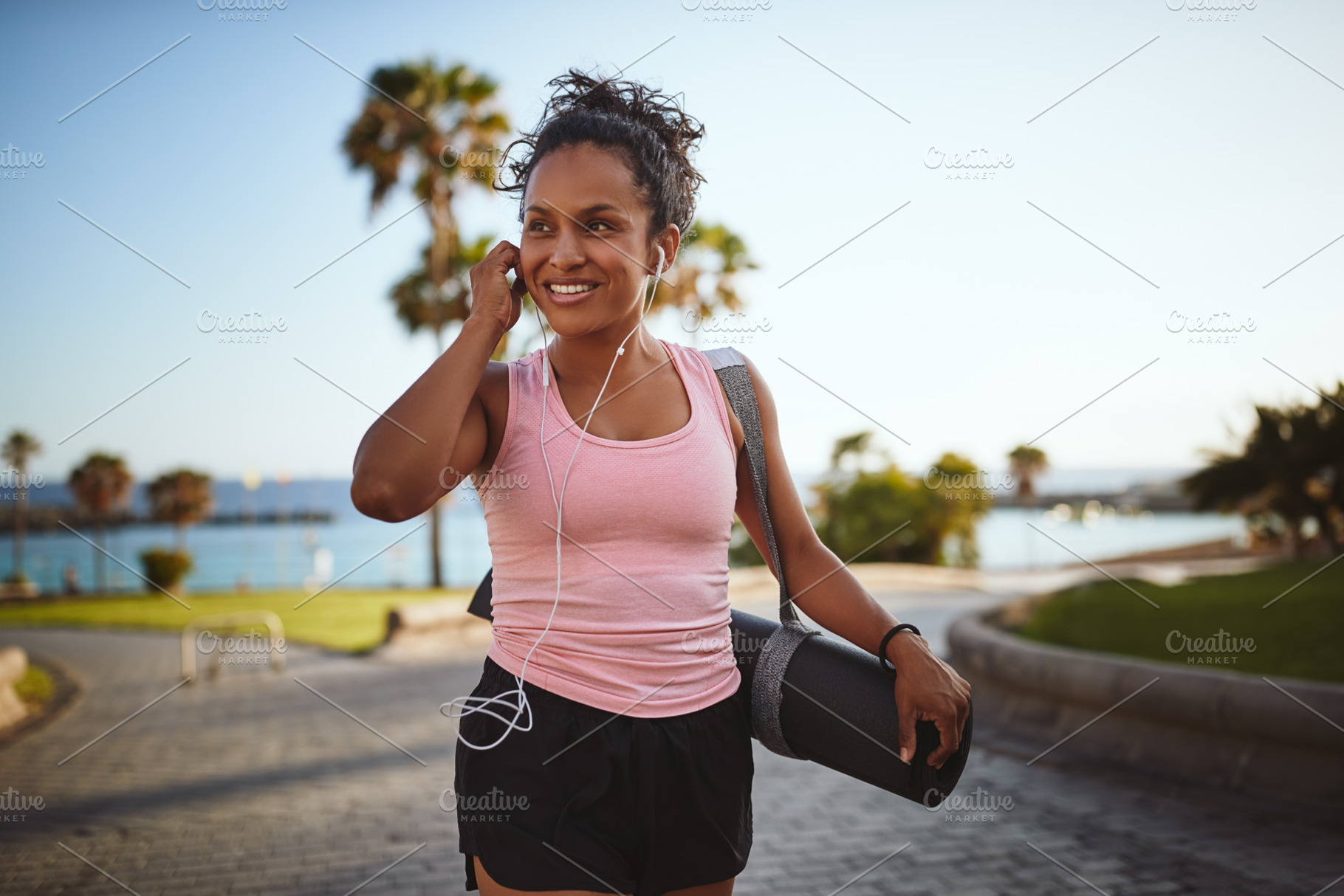 Sporty woman listening to music while carrying her yoga mat, a Sports & Recreation Photo by Stefan & Janni