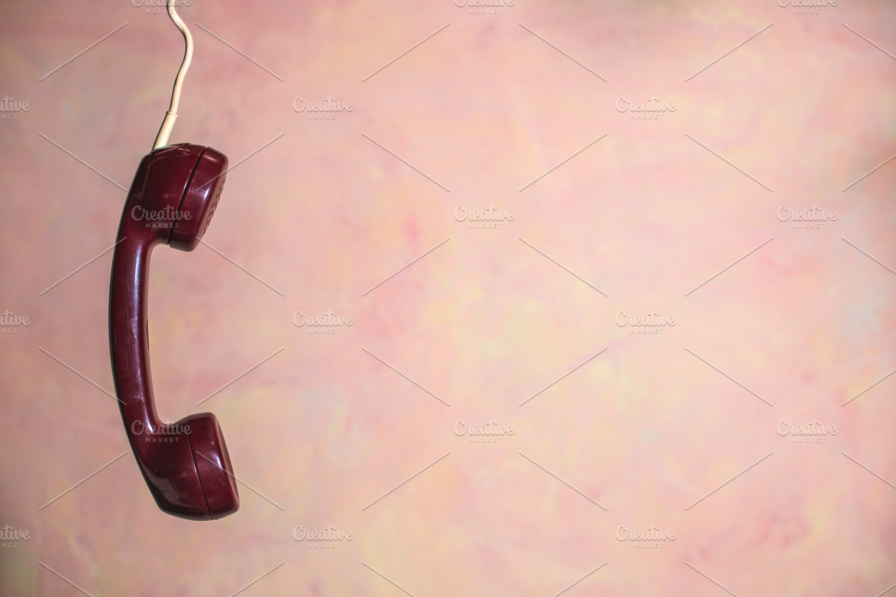 Red phone handset and pink wall containing phone, telephone, and handset, an Industrial Photo by DegImages