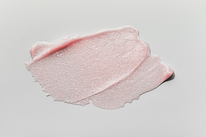 Smears of transparent pink lip gloss or moisturizer with glitter on grey backgr