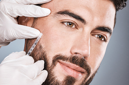 Filler, man and facial injection for skincare, collagen and beauty clinic in studio. Plastic surgery, face needle and male aesthetic for body transformation, cosmetics change and botox on background, a Photo by Peopleimages.com