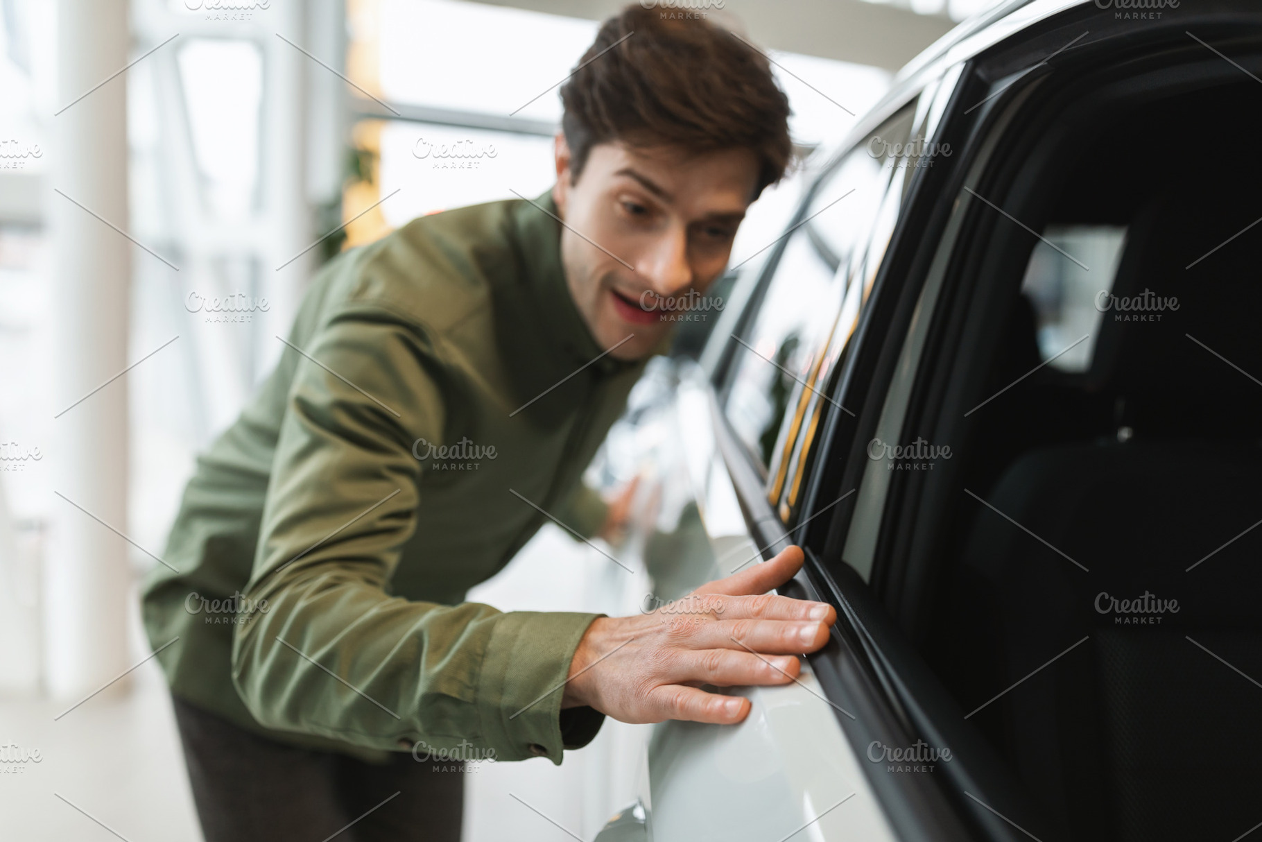 Happy young man touching new automobile of his dreams, buying modern car at dea, a Photo by Prostock-Studio