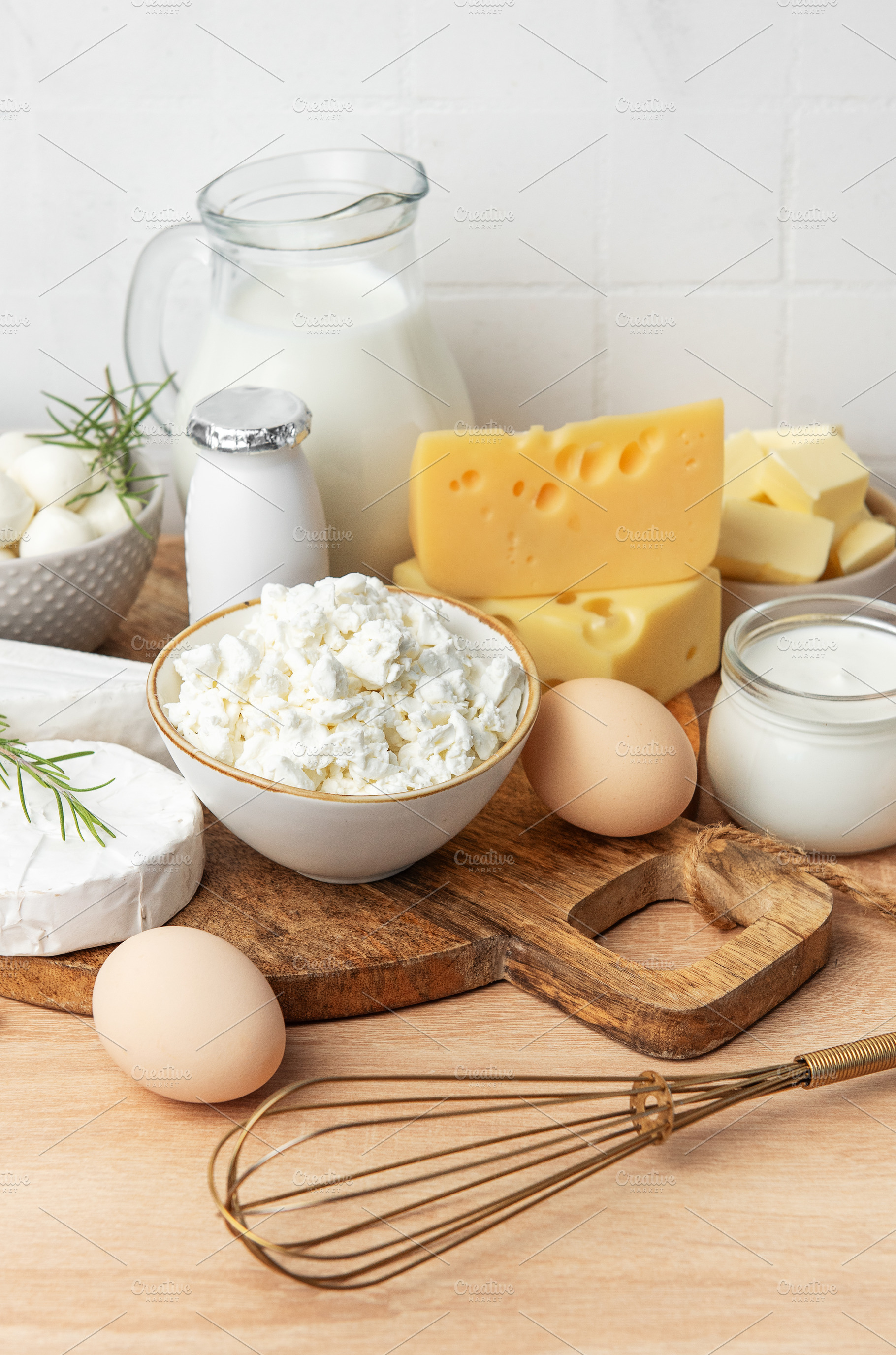 Assortment of fresh dairy products and eggs on wooden board, a Food & Drink Photo by Olena Rudo