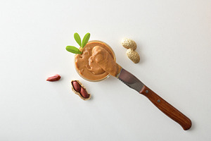 buttered knife resting on a bowl of peanut butter isolated, a Food & Drink Photo by Davizro's Market