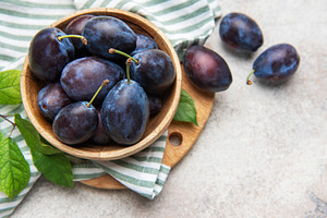 Fresh ripe plums filling a wooden bowl, a Food & Drink Photo by Olena Rudo