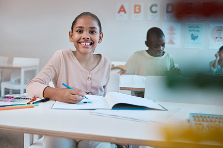 Education, class and portrait of child with smile in classroom learning reading, writing and math in Montessori school. Books, students and happy girl at desk with notebook studying for future exam., a Photo by Peopleimages.com