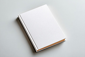 Simple closed hardcover book resting on a light gray surface without any visibl, a Background Photo by AlyaAnd