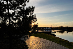 Peaceful riverside path at sunset with view of serene nature and trees, a Photo by AS photostudio