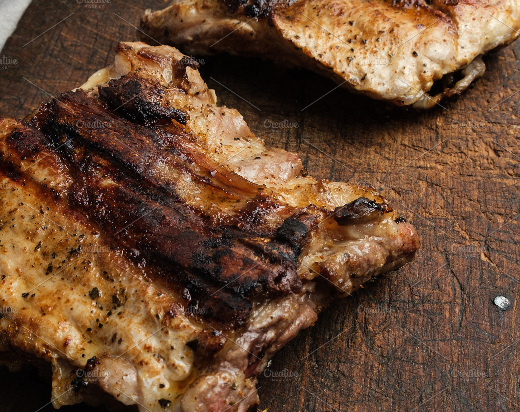 Two pieces of fried meat on an old wooden board, a Food & Drink Photo by ndanko