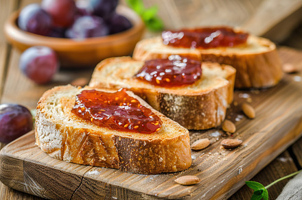 Toast breads with sweet plum jam on wooden table, a Food & Drink Photo by AlyaAnd